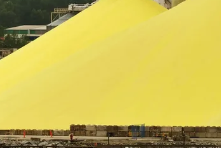 Sulphur as industrial commodity for export in bulk being loaded with an excavator