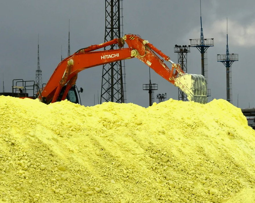 Sulphur as industrial commodity for export in bulk being loaded with an excavator